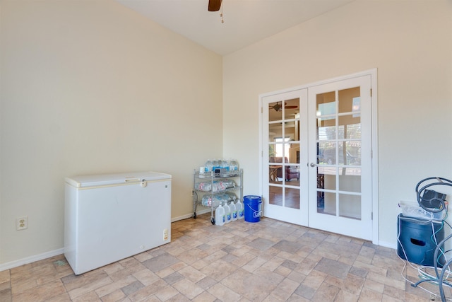 spare room featuring french doors, stone finish flooring, baseboards, and ceiling fan