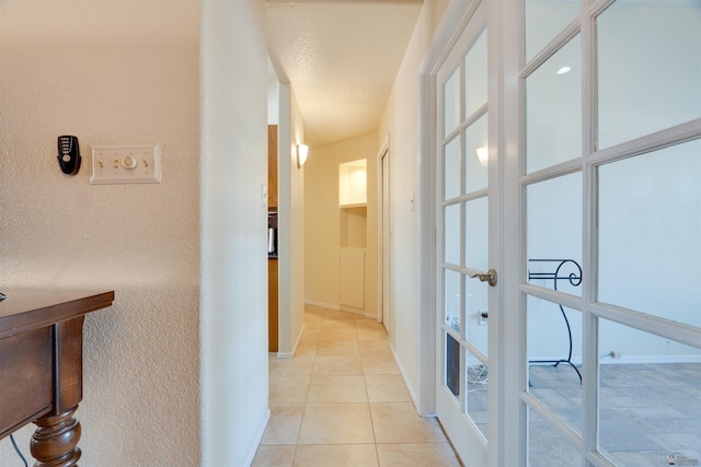 hallway featuring french doors, baseboards, and light tile patterned floors