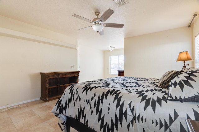 bedroom featuring light tile patterned floors, visible vents, baseboards, ceiling fan, and a textured ceiling