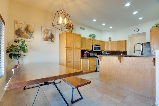 kitchen featuring a breakfast bar area, a peninsula, visible vents, appliances with stainless steel finishes, and dark countertops