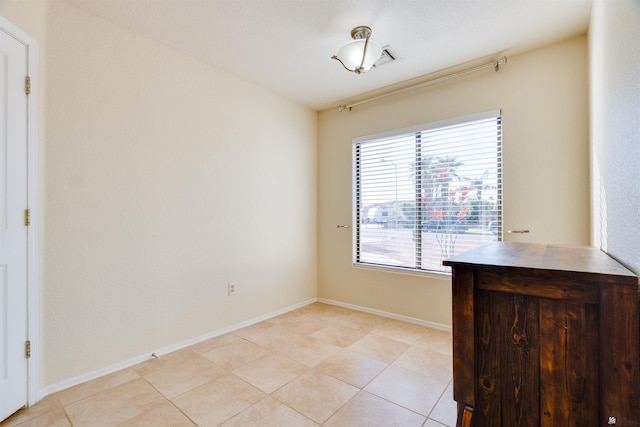 spare room featuring light tile patterned flooring and baseboards