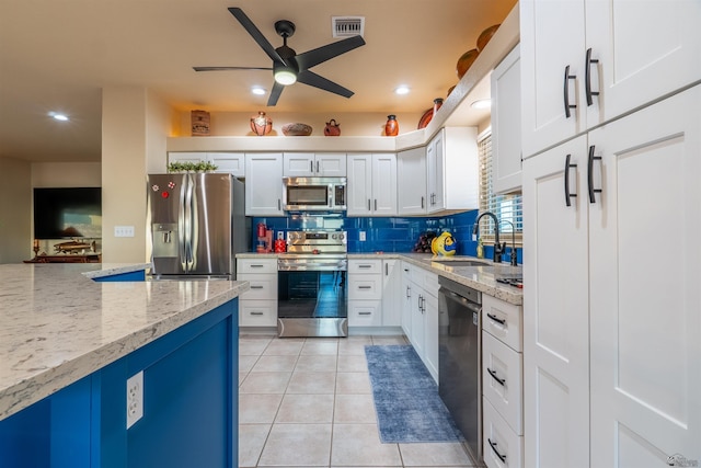 kitchen featuring sink, appliances with stainless steel finishes, white cabinetry, light stone countertops, and light tile patterned flooring