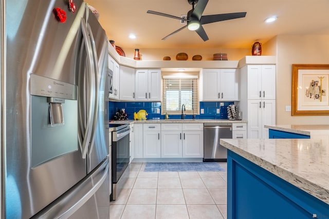 kitchen with white cabinetry, appliances with stainless steel finishes, light stone countertops, and sink