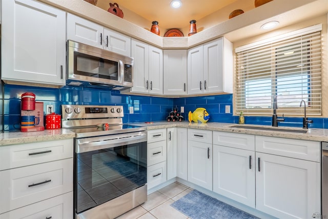 kitchen featuring light tile patterned flooring, sink, white cabinets, decorative backsplash, and stainless steel appliances