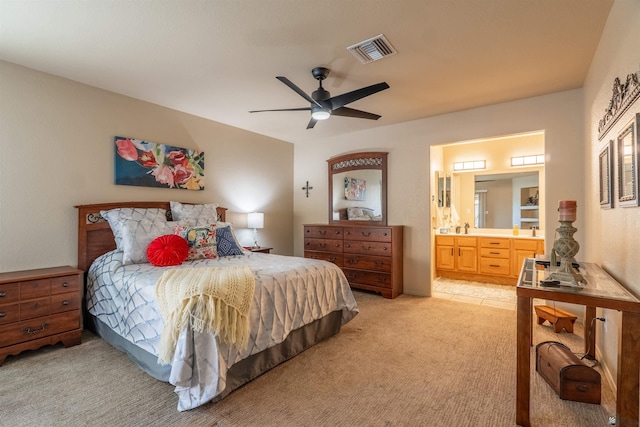 bedroom featuring ceiling fan, light colored carpet, and ensuite bathroom