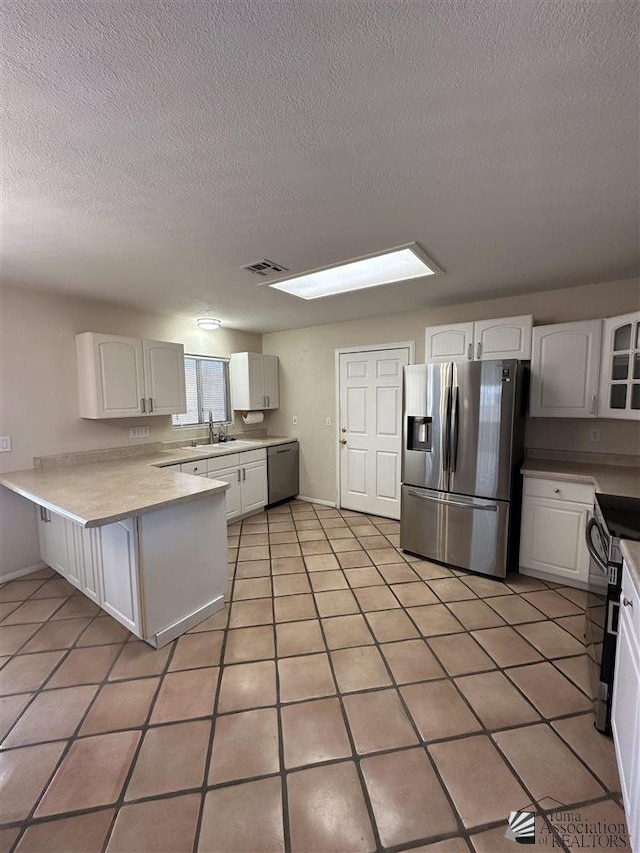 kitchen featuring white cabinets, appliances with stainless steel finishes, kitchen peninsula, and sink