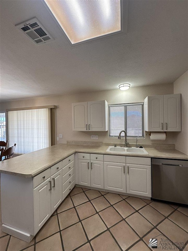 kitchen featuring light tile patterned floors, white cabinetry, stainless steel dishwasher, and sink