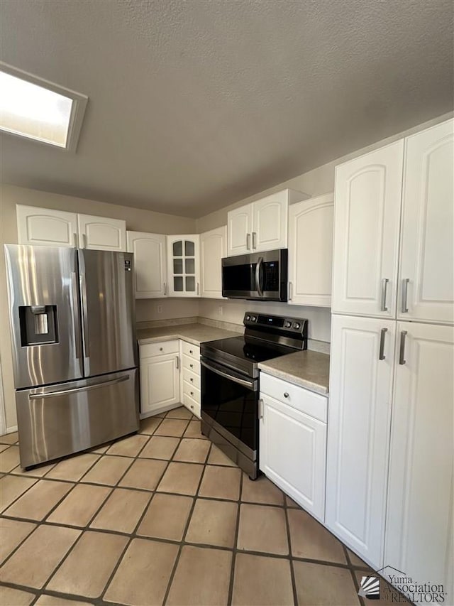 kitchen with white cabinetry, tile patterned flooring, a textured ceiling, and appliances with stainless steel finishes