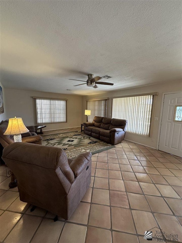 tiled living room featuring ceiling fan, a healthy amount of sunlight, and a textured ceiling