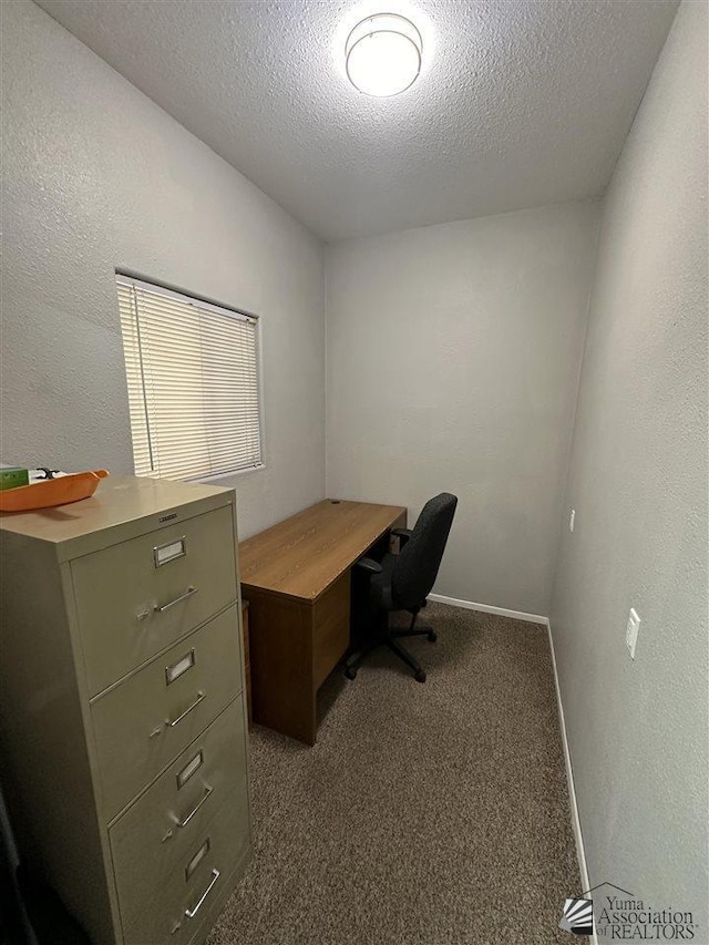 unfurnished office featuring dark carpet and a textured ceiling