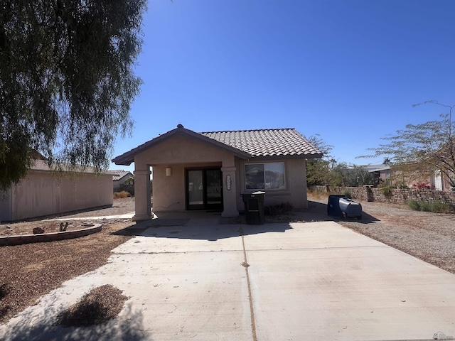 back of house featuring stucco siding, fence, and a tile roof