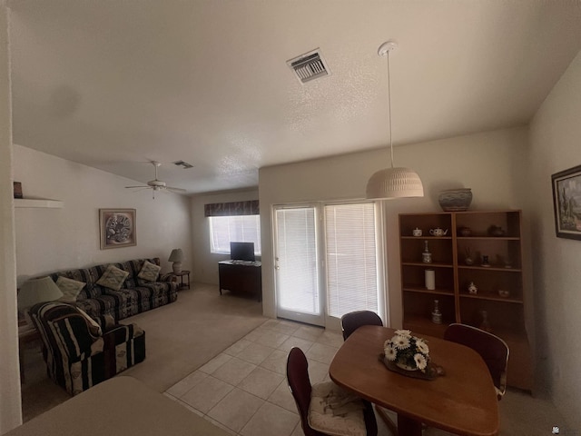 dining space featuring visible vents, light carpet, a ceiling fan, light tile patterned floors, and vaulted ceiling