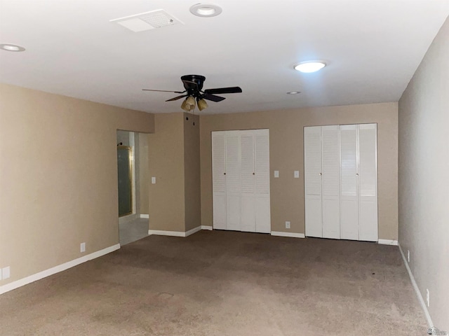 unfurnished bedroom featuring ceiling fan, carpet floors, and two closets