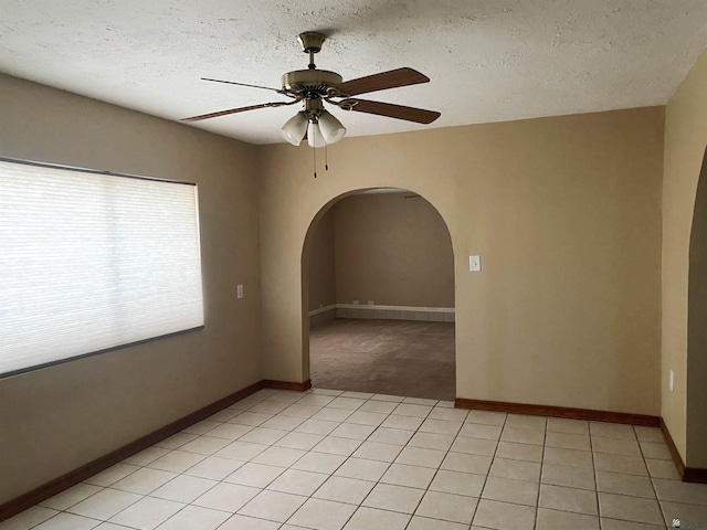 tiled empty room featuring ceiling fan and a textured ceiling