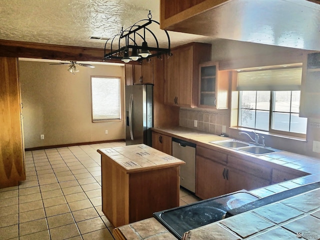 kitchen featuring stainless steel appliances, ceiling fan, sink, tile countertops, and light tile patterned flooring