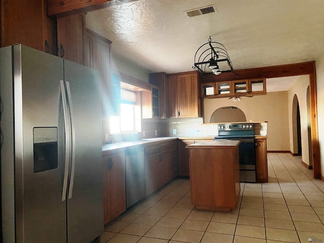 kitchen featuring decorative backsplash, stainless steel fridge, butcher block countertops, a kitchen island, and black / electric stove