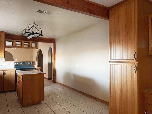 kitchen with beamed ceiling, decorative light fixtures, tasteful backsplash, and light tile patterned flooring