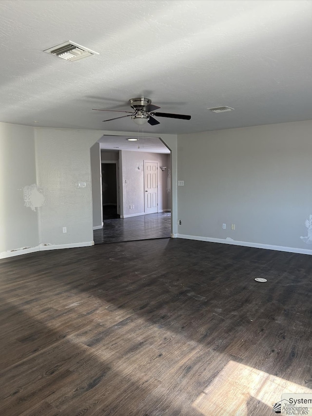 spare room with dark wood finished floors, baseboards, visible vents, and a ceiling fan