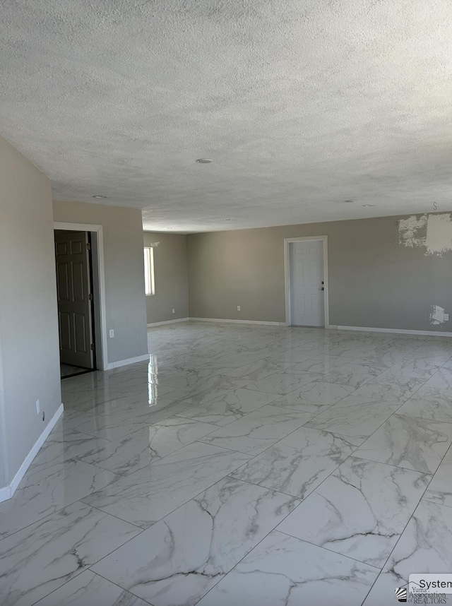 unfurnished room featuring marble finish floor, a textured ceiling, and baseboards