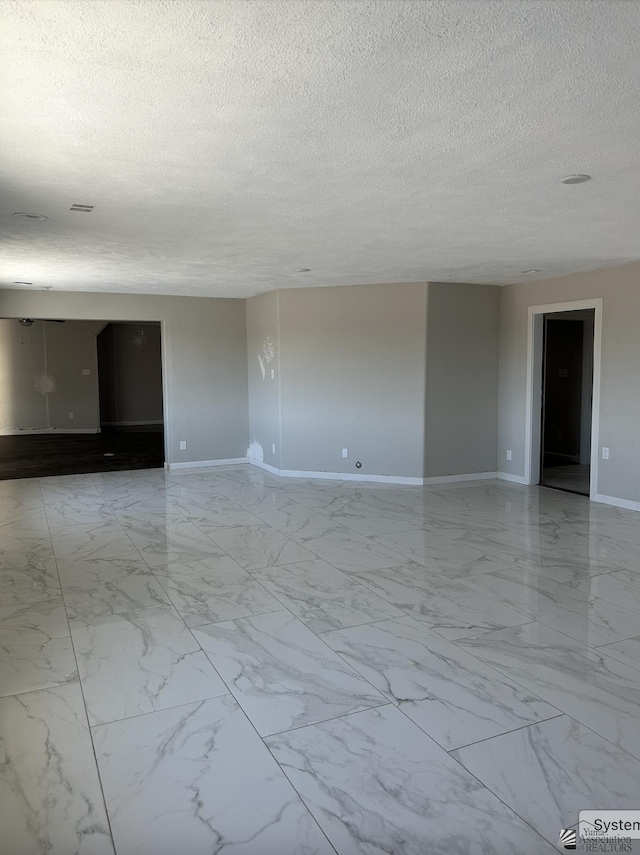 spare room with baseboards, a textured ceiling, and marble finish floor