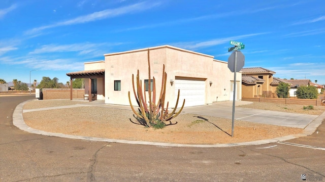 southwest-style home with driveway, fence, an attached garage, and stucco siding