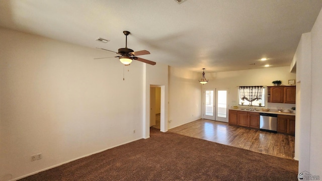 unfurnished living room featuring visible vents, ceiling fan, french doors, dark carpet, and a sink