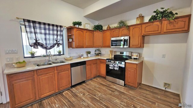 kitchen with appliances with stainless steel finishes, light countertops, a sink, and dark wood-type flooring