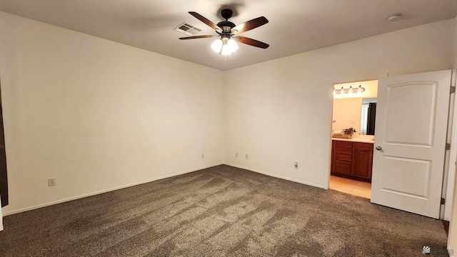 unfurnished bedroom featuring baseboards, visible vents, a ceiling fan, connected bathroom, and dark carpet