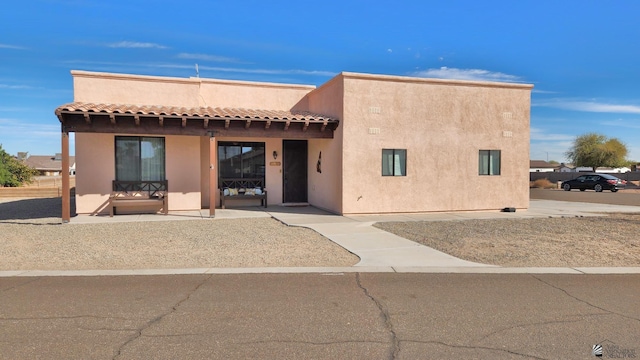 exterior space featuring a patio area, a tiled roof, and stucco siding