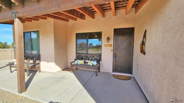 doorway to property featuring a patio area, fence, and stucco siding