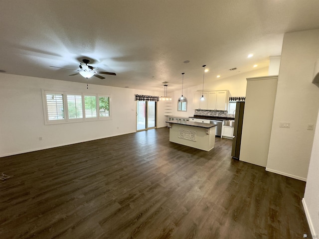 kitchen featuring dark wood-style flooring, dark countertops, backsplash, stainless steel dishwasher, and open floor plan