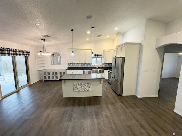 kitchen featuring stainless steel appliances, dark wood-type flooring, dark countertops, and decorative backsplash