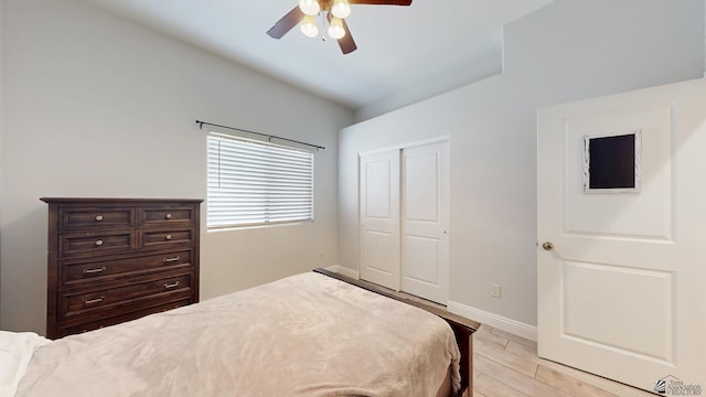 bedroom featuring a ceiling fan, light wood-type flooring, a closet, and baseboards