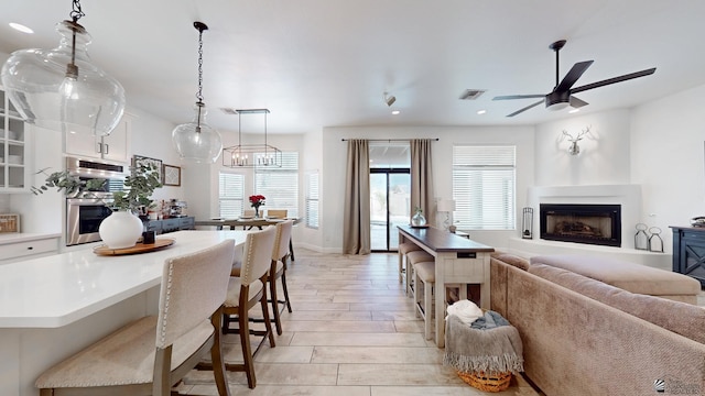 kitchen featuring white cabinets, open floor plan, decorative light fixtures, light countertops, and double oven