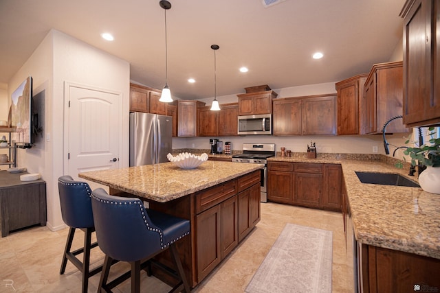 kitchen with a center island, a sink, decorative light fixtures, stainless steel appliances, and a kitchen breakfast bar