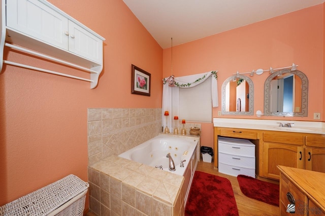 bathroom featuring tiled tub, vanity, lofted ceiling, and hardwood / wood-style flooring