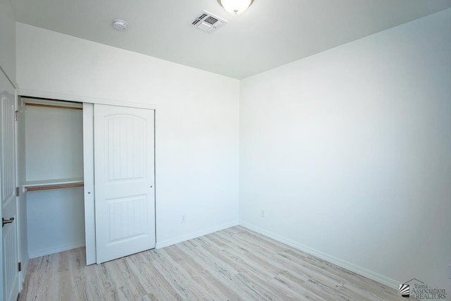 unfurnished bedroom with a closet and light wood-type flooring