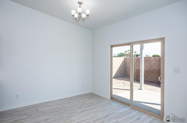 empty room with an inviting chandelier and light hardwood / wood-style flooring