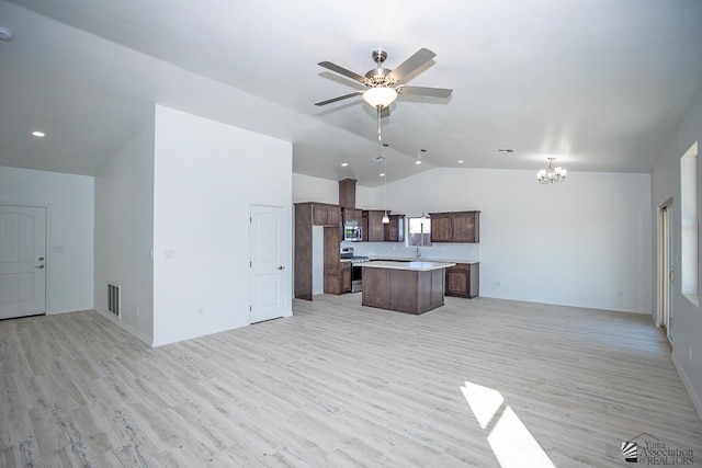 kitchen featuring lofted ceiling, pendant lighting, a center island, stainless steel appliances, and ceiling fan with notable chandelier