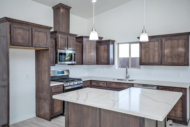 kitchen featuring decorative light fixtures, sink, light stone counters, and stainless steel appliances