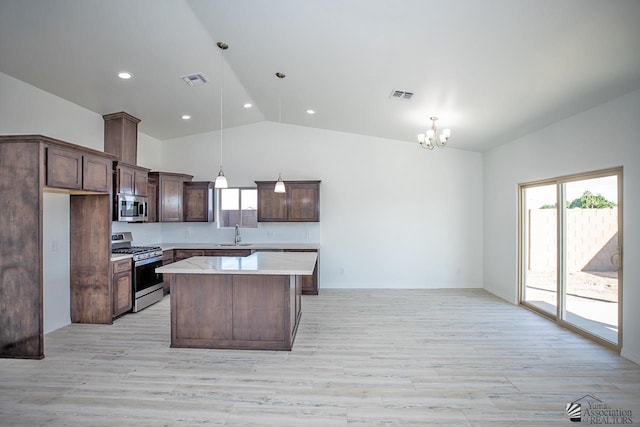 kitchen featuring a kitchen island, decorative light fixtures, stainless steel appliances, an inviting chandelier, and sink