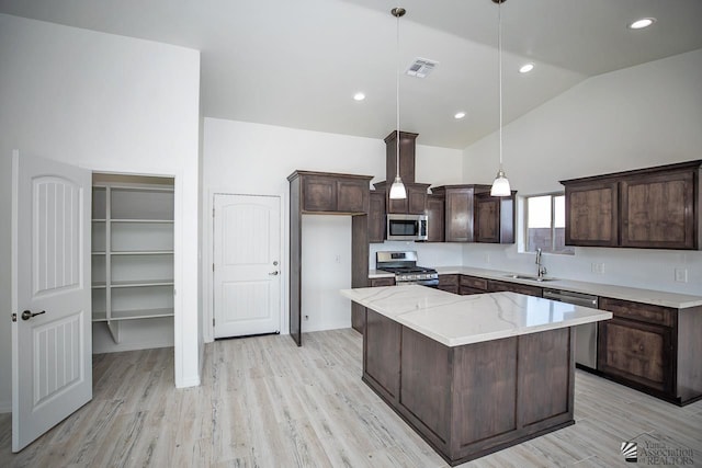 kitchen featuring vaulted ceiling, a kitchen island, sink, hanging light fixtures, and stainless steel appliances