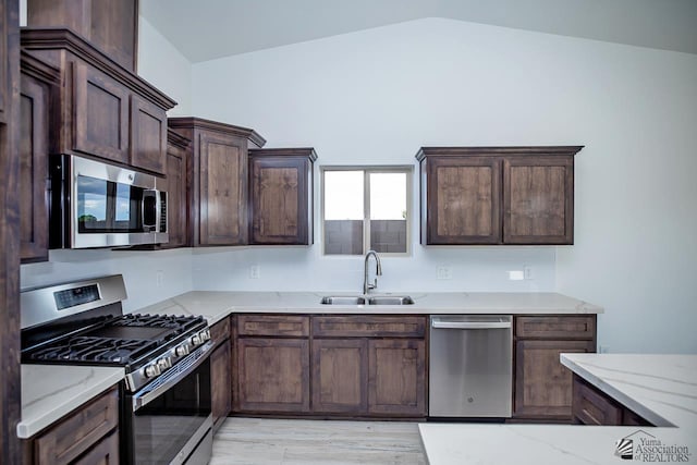 kitchen with light stone countertops, stainless steel appliances, and sink