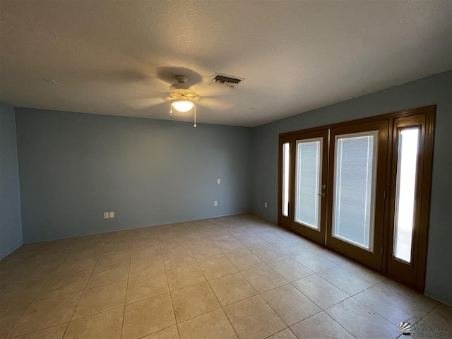 empty room featuring ceiling fan, light tile patterned floors, a textured ceiling, and french doors