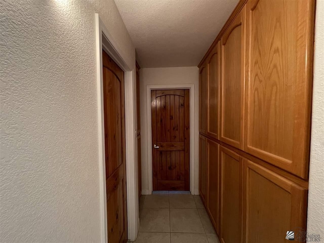 corridor featuring light tile patterned floors and a textured ceiling