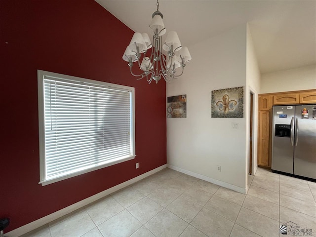 unfurnished dining area featuring light tile patterned floors, a chandelier, and vaulted ceiling