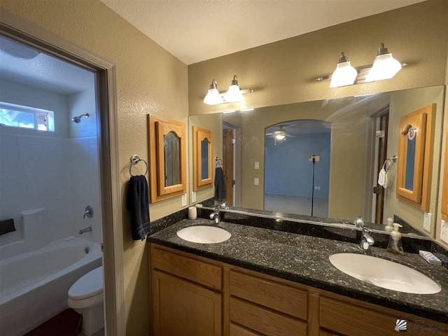 full bathroom featuring ceiling fan, shower / bath combination, a textured ceiling, toilet, and vanity