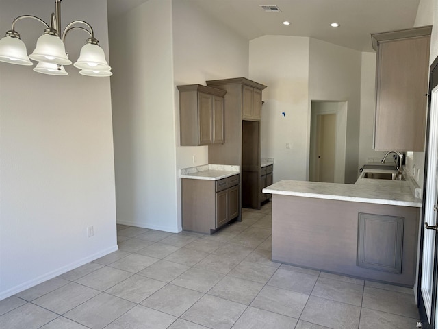 kitchen with pendant lighting, sink, a towering ceiling, light tile patterned floors, and an inviting chandelier