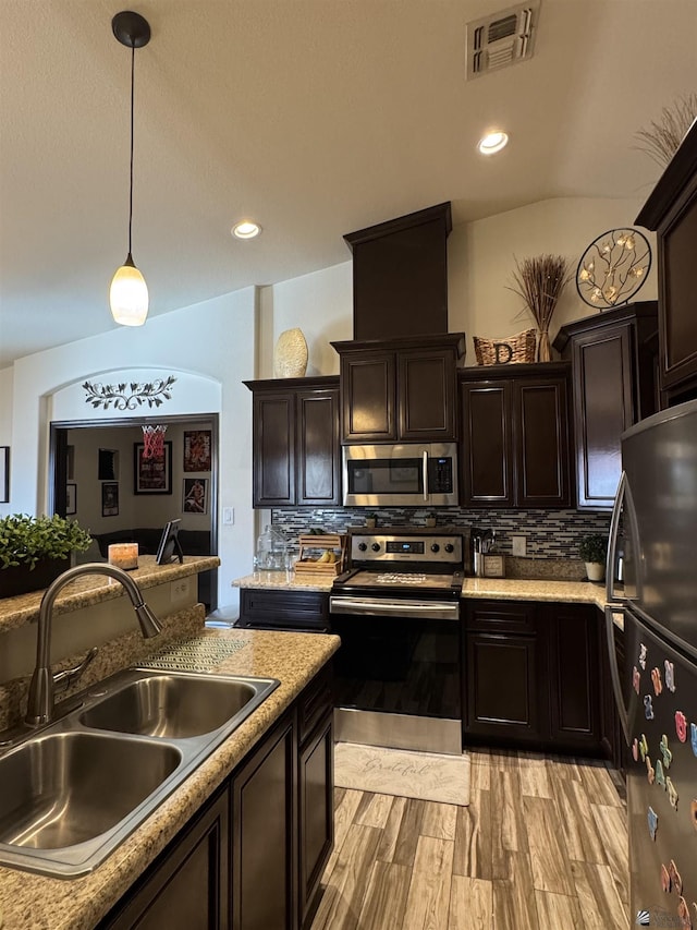 kitchen with sink, dark brown cabinets, stainless steel appliances, decorative backsplash, and decorative light fixtures