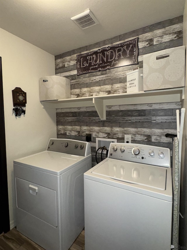 laundry area with dark wood-type flooring, washing machine and dryer, and wood walls